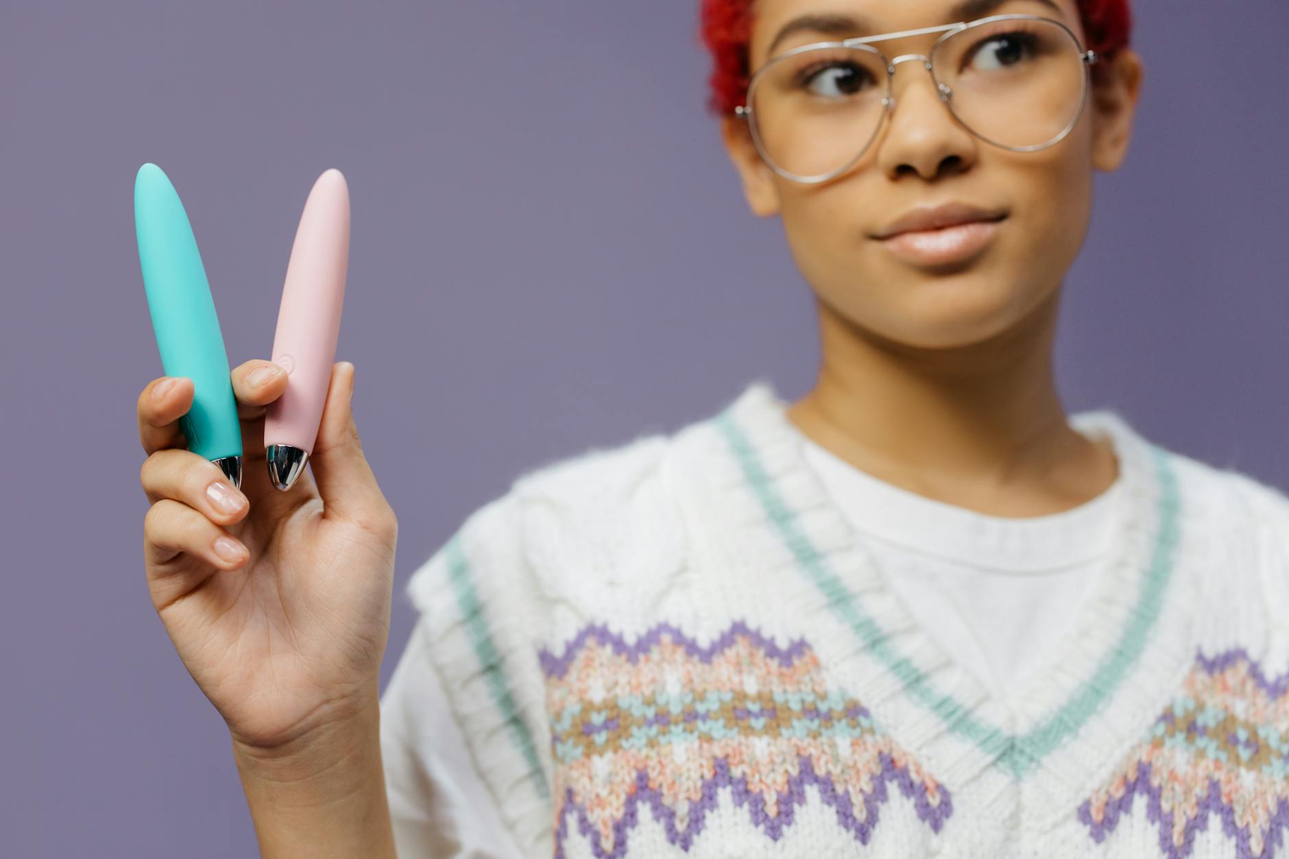 2つのカラフルなバイブレーターを持つ女性のクローズアップ