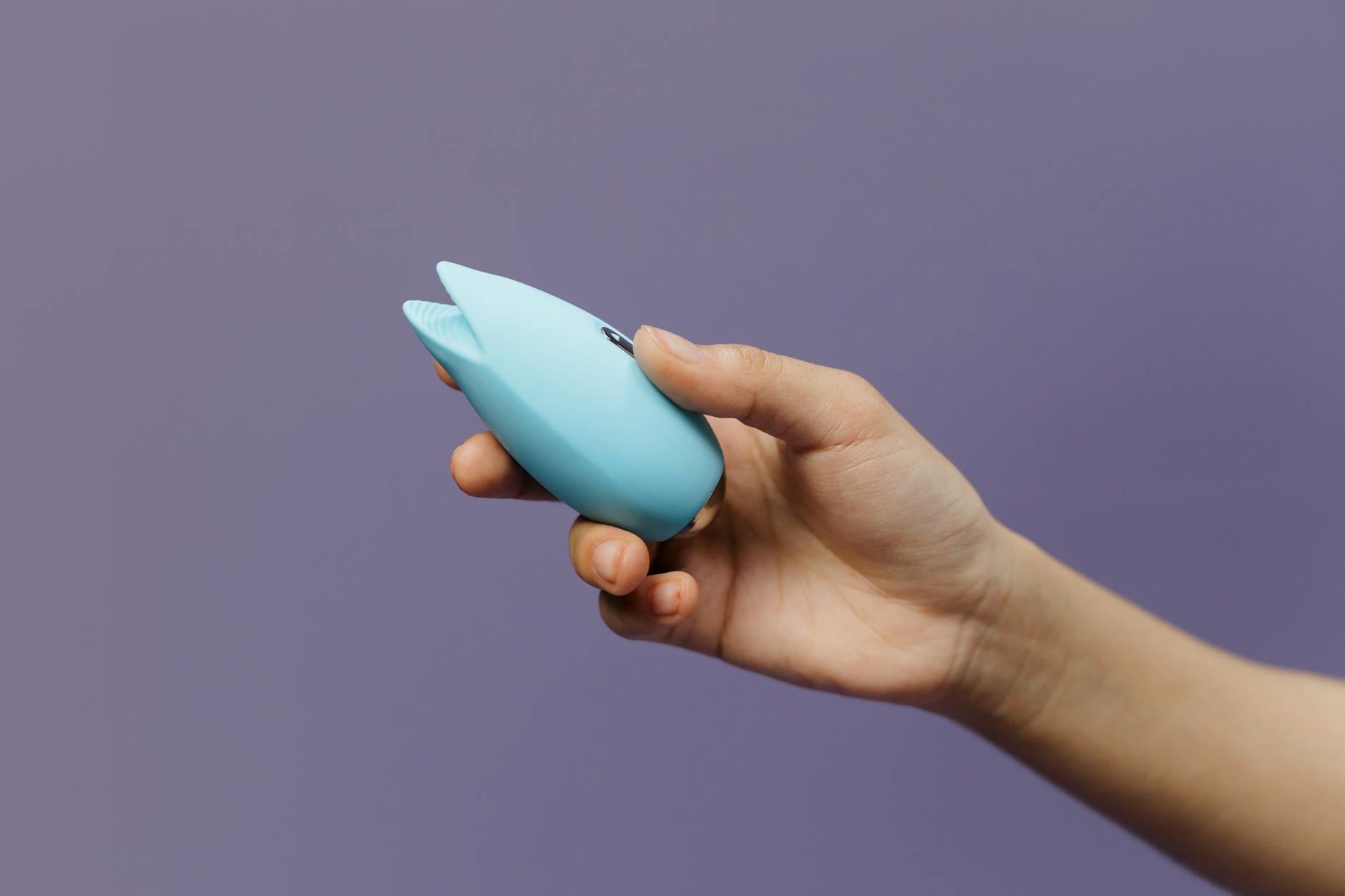 Yellow lemon clitoral vibrator surrounded by fresh fruit on a bright background