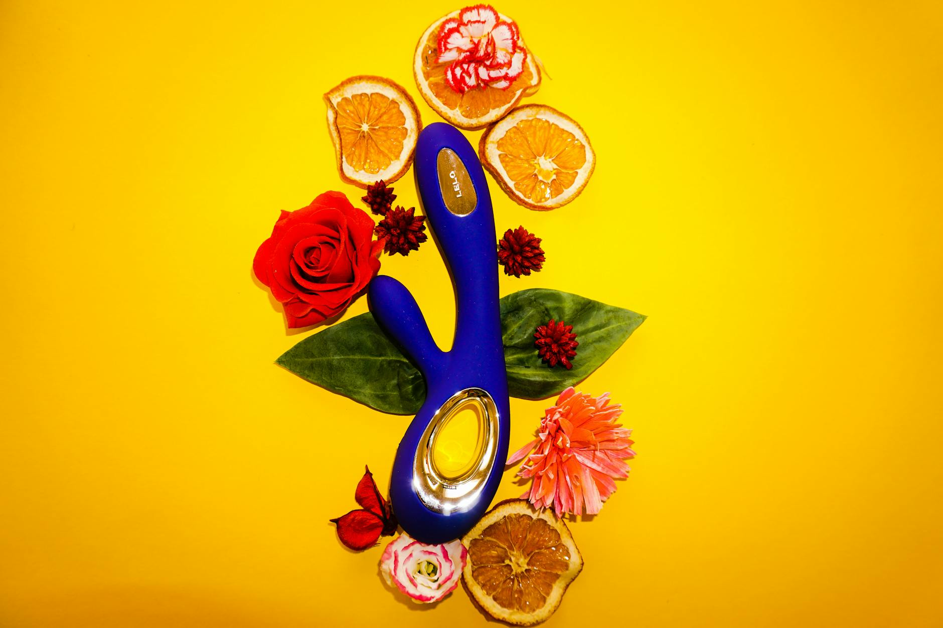 A blue clitoral vibrator held in hand against a purple background