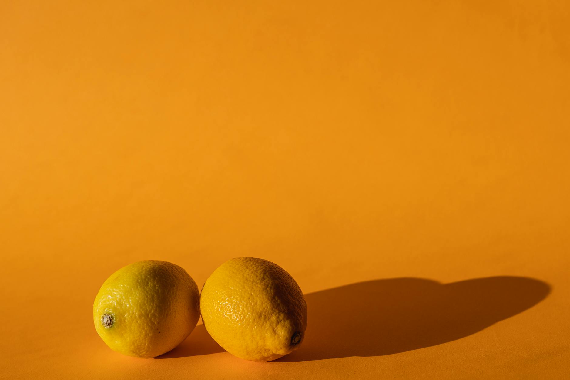 Close-up of a hand holding a lemon-colored vibrator against a minimalistic purple backdrop